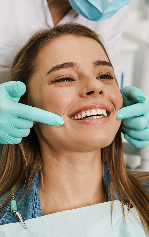 Dentist pulling back female patients lips to show their teeth