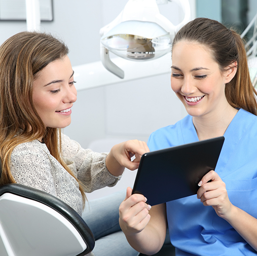 Female dentist showing female patient a tablet