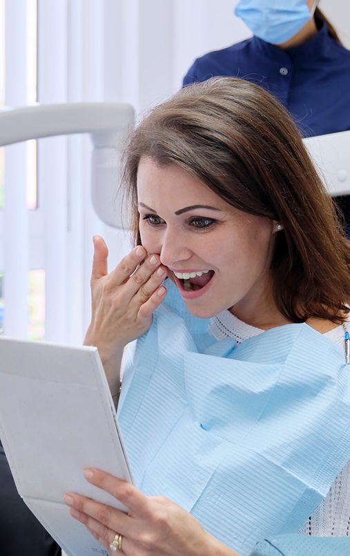 Female dental patient excitedly checking smile in mirror