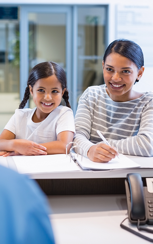 Woman and young girl sitting next to each other and smiling