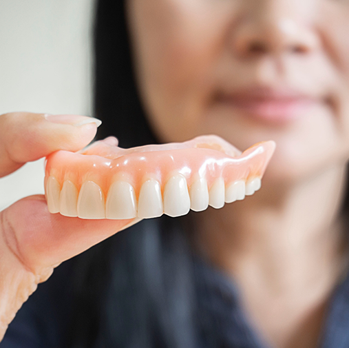 Close up of woman holding a full denture