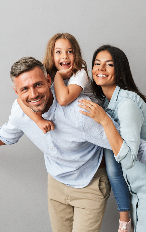 Man and woman with man giving young girl a piggyback ride