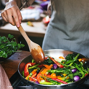 Person wearing apron while cooking vegetables