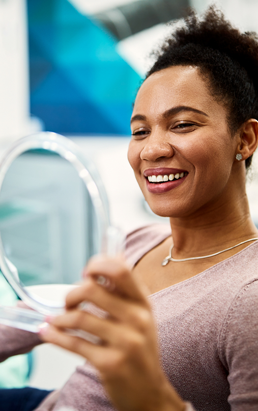 Female dental patient checking smile in mirror