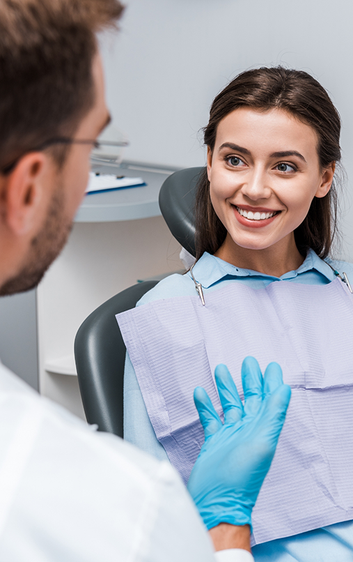 Woman in dental chair smiling and looking at dentist